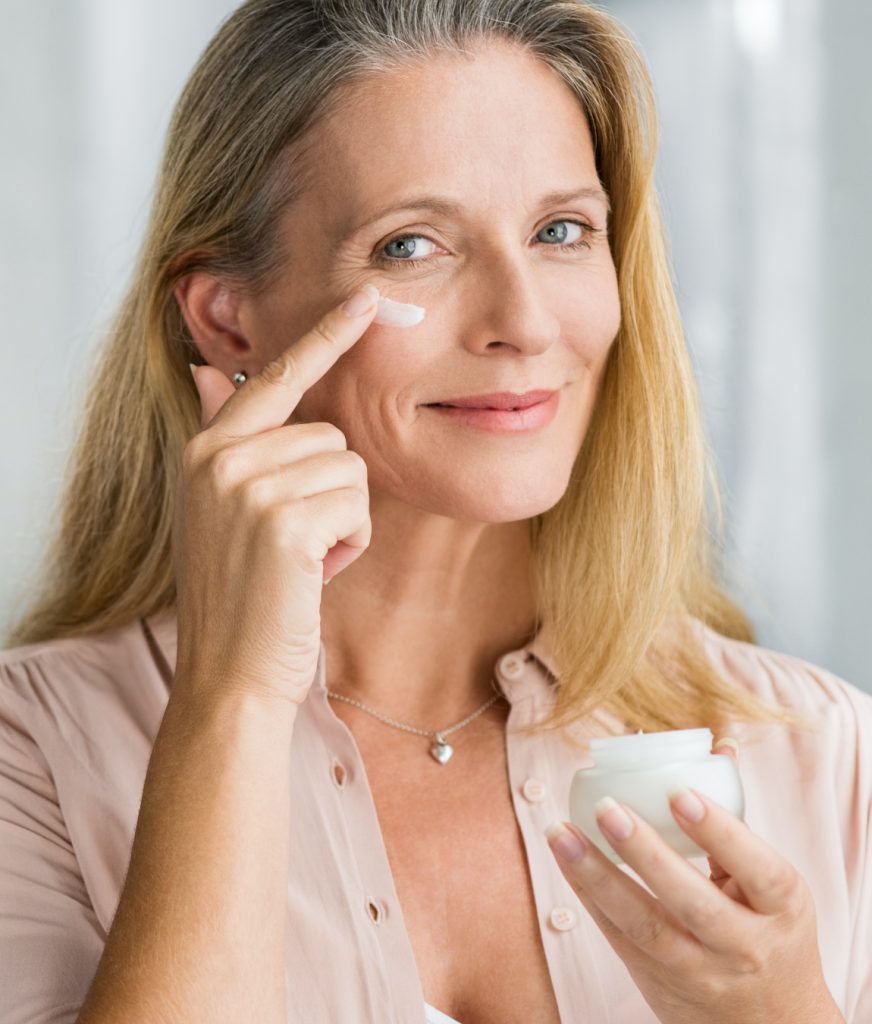 Older woman applying cream to her face