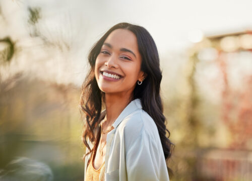 Photo of a smiling woman standing outside in the sun